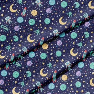 以下が含まれることがあります： 濃い青色の生地に、宇宙をテーマにしたイラストが繰り返されるパターン。ロケット、惑星、笑顔の太陽、三日月、星、漫画の宇宙飛行士が、赤、黄、緑、紫などの様々な色で描かれています。