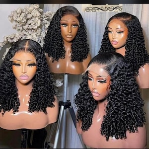 May include: Four black curly wigs on mannequin heads. The wigs feature a lace front and are styled with voluminous curls. The mannequins have makeup and are on stands, highlighting the wigs' texture and style. The wigs are a dark shade.