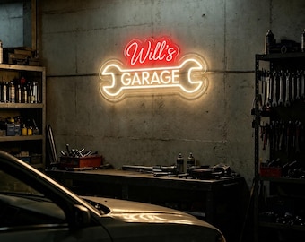 May include: A wall-mounted neon sign shaped like a wrench with the red script text Will's and the white block text GARAGE centered inside the wrench outline. The sign emits a bright glow against a gray concrete wall in a workshop setting.