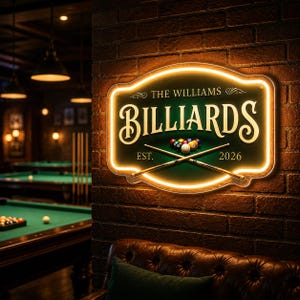 May include: A rectangular, illuminated sign with the word "BILLIARDS" in a vintage font. The sign also includes the text "THE WILLIAMS" and "EST. 2026". The sign is mounted on a brick wall, with a pool table visible in the background.