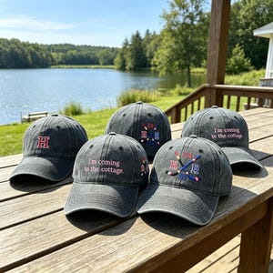 Könnte beinhalten: Eine weiße Keramik-Tasse mit schwarzem Henkel und dem Text "But First, Coffee" in fetter, schwarzer Schrift. Die Tasse steht vor einem verschwommenen Hintergrund, der eine gemütliche Umgebung suggeriert.