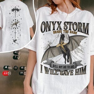 May include: White t-shirt featuring a black dragon graphic with the text "ONYX STORM BRAVE THE DARK" and "I WILL SAVE HIM". The back of the shirt has a matching dragon design.