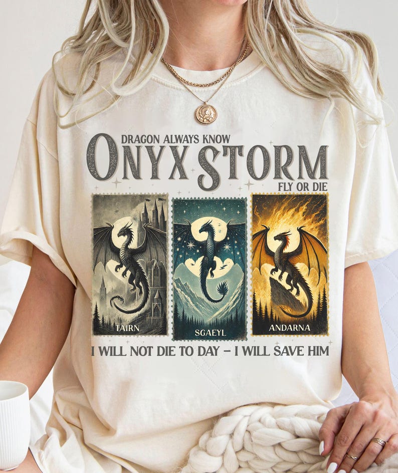 K&ouml;nnte beinhalten: Cremefarbenes T-Shirt mit einem Drachen-Design. Das Shirt zeigt den Text "DRAGON ALWAYS KNOW ONYX STORM FLY OR DIE" &uuml;ber drei Drachenillustrationen. Unter den Illustrationen steht "TAIRN", "SGAEYL" und "ANDARNA". Der Text unten lautet "I WILL NOT DIE TO DAY - I WILL SAVE HIM".