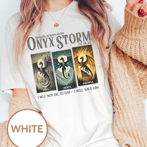 K&ouml;nnte beinhalten: Wei&szlig;es T-Shirt mit einem grafischen Design, das drei Drachenillustrationen im Poststempelstil zeigt. Der Text "ONYX STORM" und "DRAGON ALWAYS KNOW" sind &uuml;ber den Bildern aufgedruckt. Unter den Bildern steht der Text "I WILL NOT DIE TO DAY - I WILL SAVE HIM".