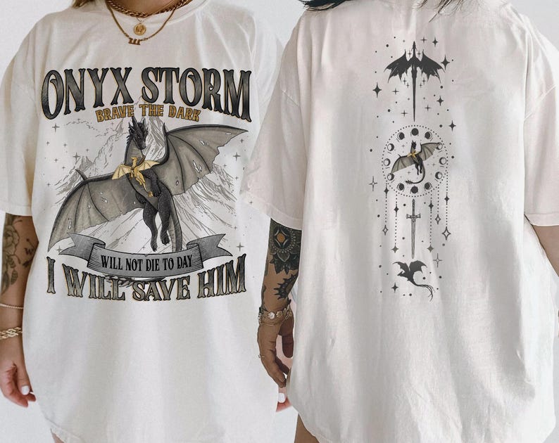 May include: Cream-colored t-shirt featuring a black dragon graphic with the text "ONYX STORM" and "BRAVE THE DARK". Below the dragon is the text "WILL NOT DIE TO DAY I WILL SAVE HIM". The back of the shirt has a matching dragon and celestial design.