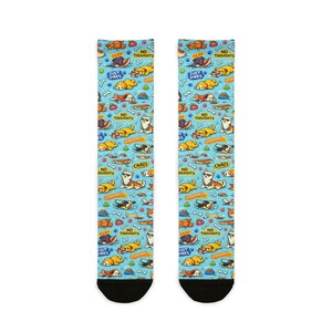Könnte beinhalten: Ein Paar Socken mit einem sich wiederholenden Muster von Cartoon-Hunden auf hellblauem Hintergrund. Die Socken zeigen Texte wie "DERP", "NO THOUGHTS", "JUST VIBES" und "CHAOS".