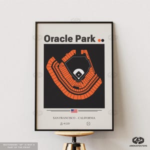 May include: A framed poster featuring a stylized orange and black illustration of Oracle Park, a baseball stadium. The poster includes the text "Oracle Park" at the top, and "SAN FRANCISCO - CALIFORNIA" at the bottom, along with the stadium's seating capacity and a baseball icon.