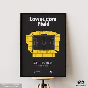 May include: A framed black poster featuring a top-down view of Lower.com Field in Columbus, Ohio. The stadium is rendered in yellow against a black background. Text includes "Lower.com Field" and "Columbus, State of Ohio."