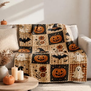 May include: A rectangular throw blanket featuring a patchwork design of Halloween-themed squares. The pattern includes orange jack-o'-lanterns, white ghosts, black bats, witch hats, and brown flowers set against black and tan plaid backgrounds.