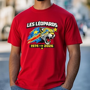 May include: Red t-shirt featuring a graphic of a roaring leopard with the text "LES LÉOPARDS" above and "1974→2026" below. The leopard graphic incorporates the colors of a flag, with blue, yellow, and red elements.