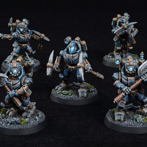 May include: Five miniature figures in blue and brown armor, each posed on a circular base. The figures are holding various tools, including a pickaxe and a hammer. The figures have glowing blue accents. The logo "Da Gobbo Printz" is in the lower left.