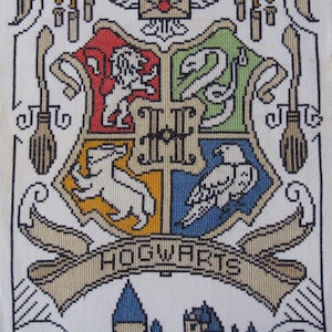 May include: A cross-stitch of the Hogwarts crest, featuring the four houses: Gryffindor, Slytherin, Hufflepuff, and Ravenclaw. The crest is surrounded by candles, brooms, and the Hogwarts castle. The word "Hogwarts" is displayed on a banner.