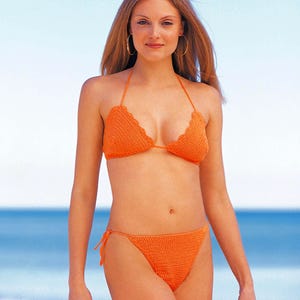 May include: A bright orange two-piece bikini set crafted from crochet fabric. The top features a classic triangle design with scalloped edges and thin halter straps. The matching bottom includes side tie closures for an adjustable fit.