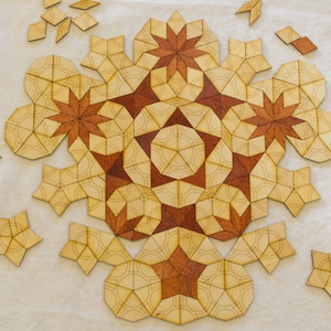 May include: A geometric wooden puzzle with light and dark brown pieces. The design features star and floral shapes, with some pieces scattered around the central pattern. A craft or educational item, with pieces measured in cm.
