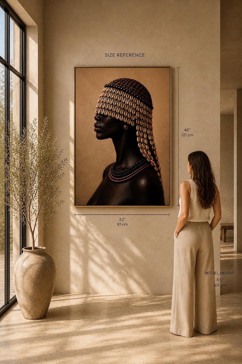May include: A framed portrait print of a person in profile wearing a cowrie shell headpiece and layered beaded necklaces. The artwork measures 32 inches wide by 48 inches high, displayed on a wall next to a person who is 65 inches tall.