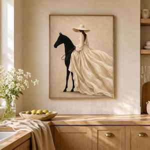 May include: A framed wall art print featuring a silhouette of a black horse and a figure wearing a wide-brimmed hat and a long, flowing cream-colored dress. The artwork is rendered in a neutral color palette with soft beige and cream tones.