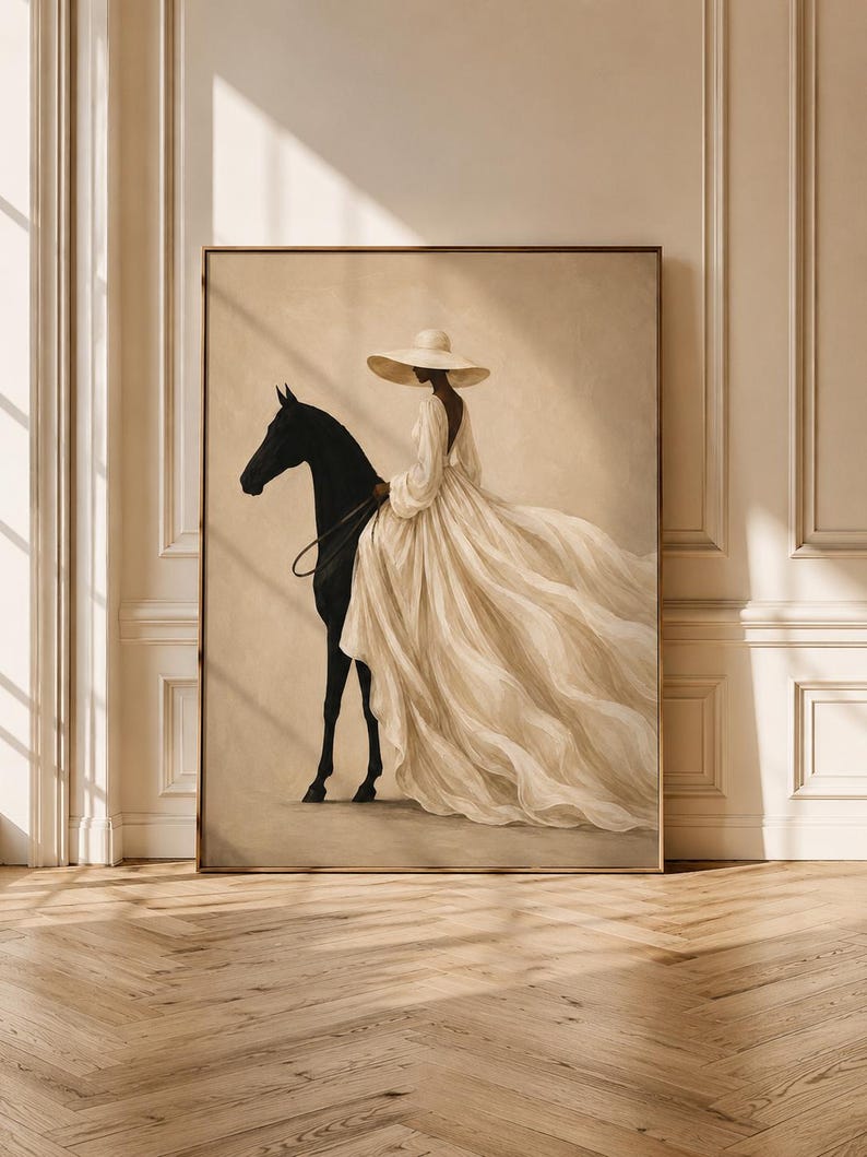 May include: A framed wall art print depicting a figure wearing a wide-brimmed hat and a long, flowing cream-colored gown while standing beside a solid black horse. The artwork features a neutral beige background and soft, diffused lighting.
