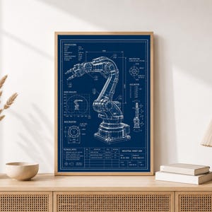 May include: A framed blueprint poster featuring a detailed technical drawing of an industrial robot arm in white lines on a dark blue background. The print includes various specifications, diagrams, and technical notes labelled Industrial Robot Arm.