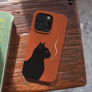 May include: A burnt orange smartphone case featuring a graphic illustration of a black cat in profile. The cat has yellow eyes and is holding a lit cigarette in its mouth, with a thin trail of white smoke rising upward against the orange background.