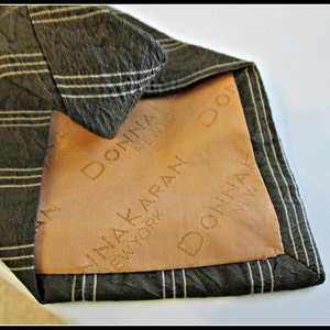May include: A black and white striped tie with a brown lining. The lining has the text "Donna Karan New York" printed on it.