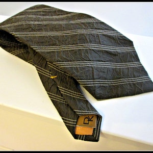May include: A dark brown striped tie with a brown leather tag that says "DK".