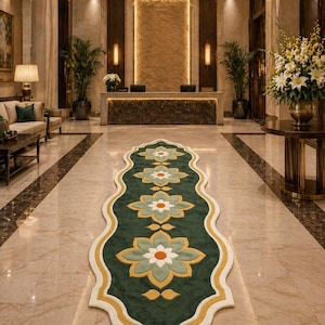 May include: A luxurious hotel lobby featuring a long, green runner rug with a floral pattern. The rug has a cream-colored border and is centered on a polished marble floor. The lobby includes a reception desk, seating area, and decorative plants.