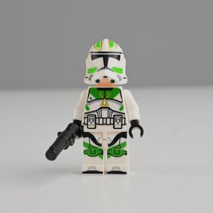 May include: A white ceramic mug with a black handle and the text "But First, Coffee" in a handwritten style. The mug is on a white surface. The mug is approximately 10 cm tall.