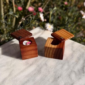 May include: A white ceramic mug with a black handle and the text "But First, Coffee" in a black, bold font. The mug is on a white surface.