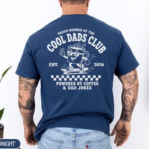 Comfort Colors 1717 Midnight t-shirt on male model featuring a white Cool Dads Club coffee mug Powered by Coffee graphic, soft unisex fit, garment dyed cotton texture, vintage washed tee for personalized dad gifts, Father's Day shirts, family style.
