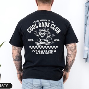 Comfort Colors 1717 Black t-shirt on male model featuring a white Cool Dads Club coffee mug Powered by Coffee graphic, soft unisex fit, garment dyed cotton texture, vintage washed tee for personalized dad gifts, Father's Day shirts, family style.