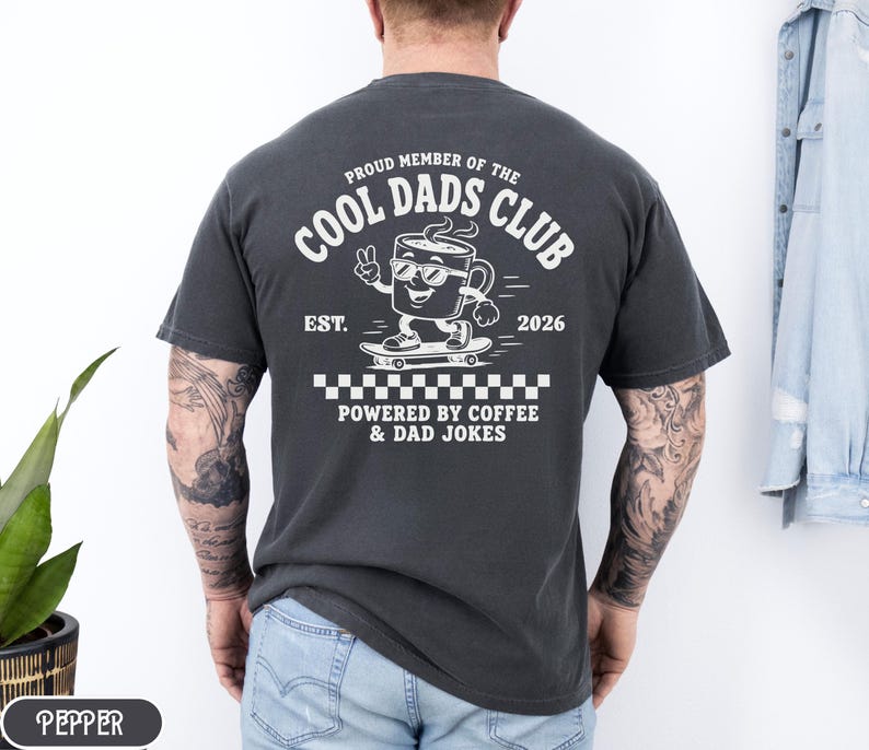 Comfort Colors 1717 Pepper t-shirt on male model featuring a white Cool Dads Club coffee mug Powered by Coffee graphic, soft unisex fit, garment dyed cotton texture, vintage washed tee for personalized dad gifts, Father's Day shirts, family style.