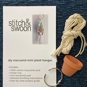 May include: DIY macrame mini plant hanger kit with white cotton cord, a terracotta pot, a metal ring, and instructions.  stitch&swoon.