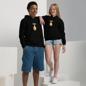 May include: Two people wearing black hoodies featuring a pineapple graphic and the text "what's one to a fool fight." The hoodies have a drawstring hood and a kangaroo pocket. One person is wearing denim shorts and the other is wearing denim shorts.