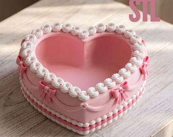 Op de afbeelding: Een hartvormige roze kom met een witte, gespoten rand in de stijl van glazuur, decoratieve roze strikjes aan de zijkanten en een geschulpte onderkant. De tekst STL is zichtbaar in de rechterbovenhoek van de afbeelding.
