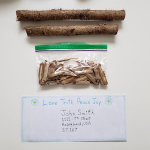 May include: An overhead shot shows two brown wooden sticks with thorns, a clear plastic bag filled with small brown wood pieces, and a handwritten note with the words "Love Truth Peace Joy".