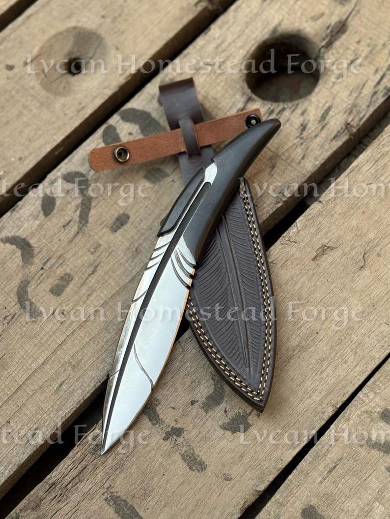 Puede incluir: Un cuchillo de hoja fija con una hoja de metal plateado en forma de pluma, con un mango oscuro y una funda de cuero marr&oacute;n oscuro a juego con detalles de plumas en relieve y una correa de cuero con botones de presi&oacute;n de metal.