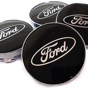 Puede incluir: Cuatro tapacubos negros Ford con el logotipo Ford plateado. Los tapacubos son redondos con un acabado brillante y un borde plateado. El logotipo de Ford está en cursiva.
