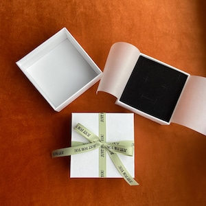 May include: A set of three ceramic mugs with a speckled, matte finish in cream, light grey, and dark grey. Each mug has a simple, minimalist design and a rounded handle.