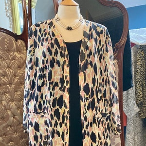 Peut inclure: Un kimono à imprimé léopard noir et blanc avec une bordure en franges noires. Le kimono est porté sur une robe noire et un collier de perles.