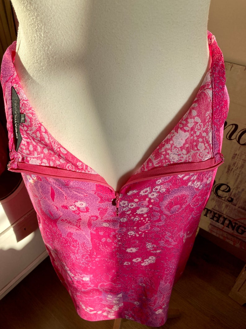 Puede incluir: Un vestido rosa sin mangas con estampado floral y cierre de cremallera. El vestido tiene un escote en V y una silueta ajustada. La etiqueta de la marca dice "Great Plains 8".