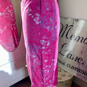 Puede incluir: Una falda rosa con estampado floral en tonos morados y blancos. La falda es de largo hasta la rodilla y tiene una silueta recta.