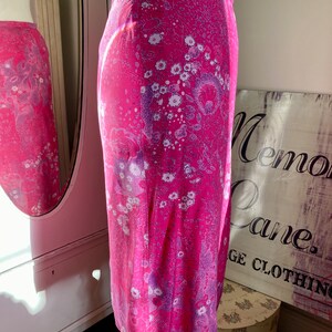 Puede incluir: Una falda rosa con estampado floral. La falda tiene un fondo blanco con flores rosas y moradas.