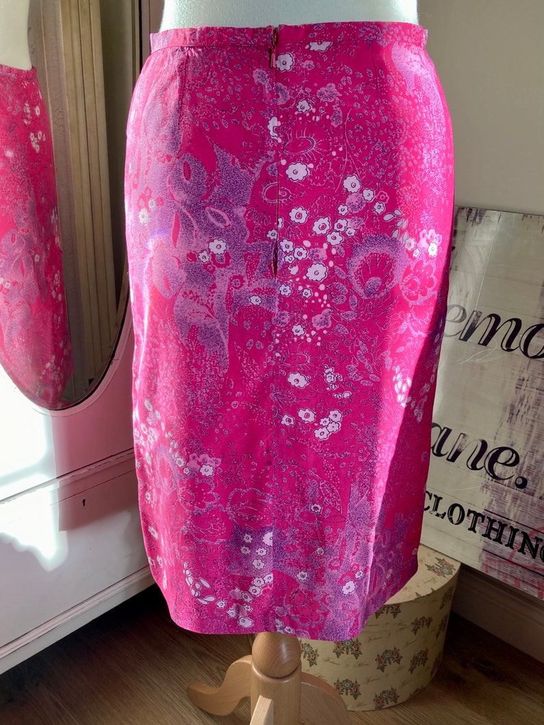 Puede incluir: Una falda rosa con estampado floral. La falda tiene una cremallera en la parte posterior.