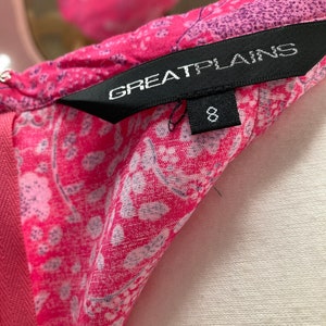 Puede incluir: Un vestido de estampado floral rosa y blanco con una etiqueta negra que dice "Great Plains" y una etiqueta de talla 8.