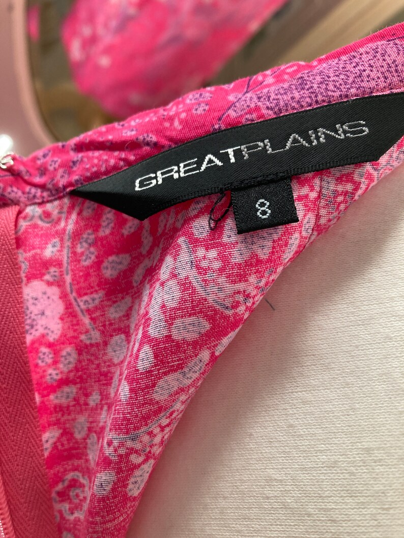 Puede incluir: Un vestido de estampado floral rosa y blanco con una etiqueta negra que dice "Great Plains" y una etiqueta de talla 8.