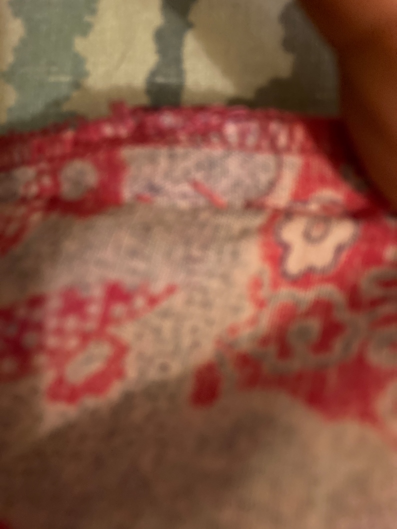 Puede incluir: Primer plano de una tela estampada en rojo y blanco con una costura rosa.