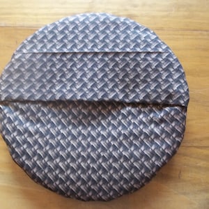 May include: A round, black and white patterned cushion with a woven design.