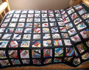 May include: Handmade quilt with a patchwork design. The quilt features a grid of black squares, each containing a unique arrangement of colorful fabric scraps. The quilt is displayed on a wooden bed frame.