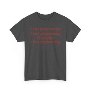 K&ouml;nnte beinhalten: Ein dunkelgraues Kurzarm-T-Shirt mit rotem Text, der lautet: I hate programming, I hate programming, &mdash; It works! &mdash;, I love programming. Das T-Shirt hat einen Rundhalsausschnitt und eine Standardpassform, wobei der Text mittig auf der Brust steht.
