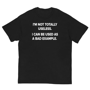 以下が含まれることがあります： 白文字で「I'M NOT TOTALLY USELESS. I CAN BE USED AS A BAD EXAMPLE.」と書かれた黒いTシャツ。